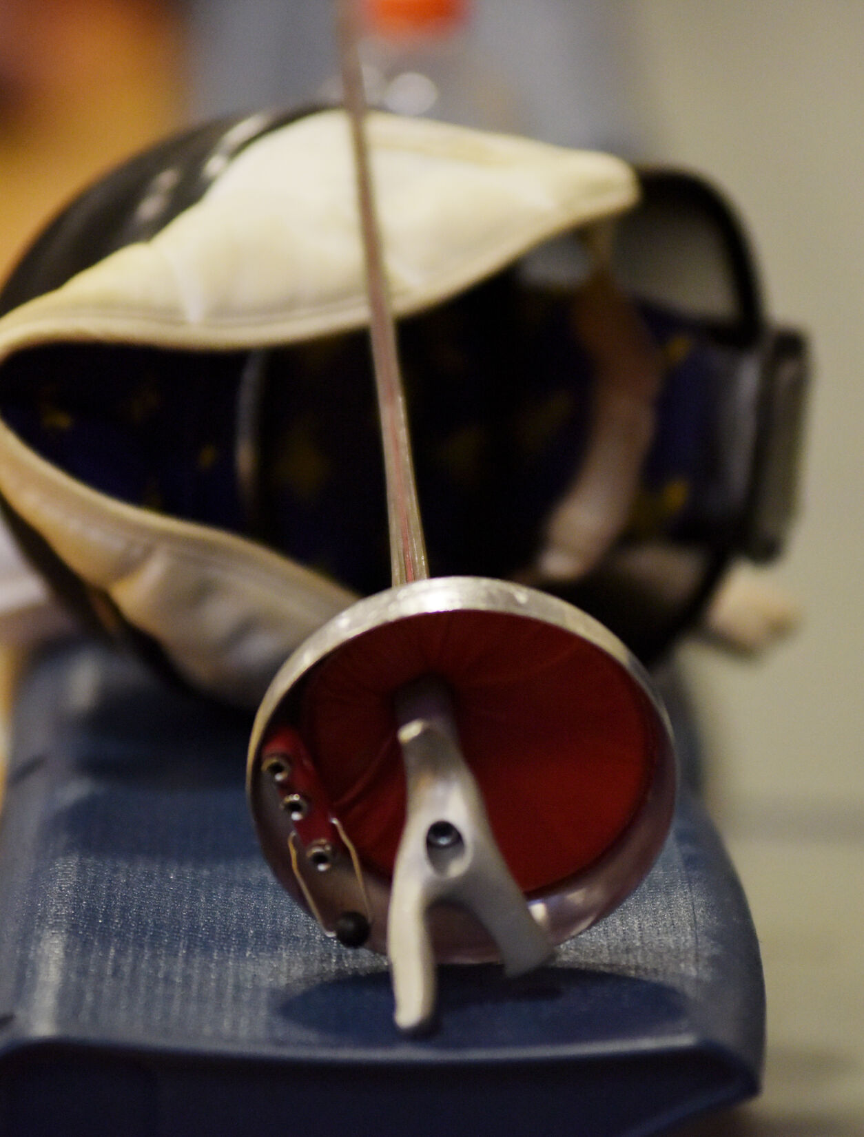 A fencing mask and foil sit on the bleachers